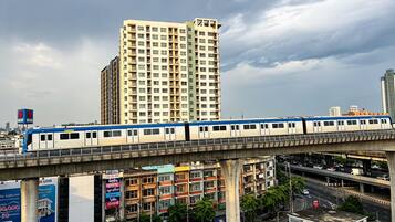 A train on an elevated track with a cityscape in the background.