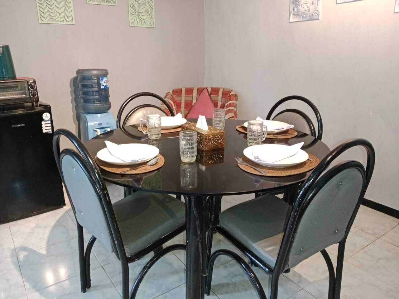 A dining area with a round table set for four, surrounded by chairs.