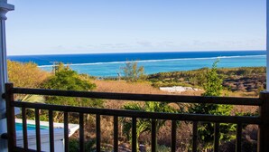 Blick vom Balkon auf eine Küstenlandschaft mit Meer und viel Grün.