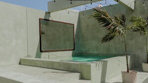 A concrete pool area with steps leading into the water, surrounded by walls and potted plants. - Hotel Florita39 (Isla Mujeres)