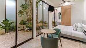 A modern bedroom with a bed, a TV, a ceiling fan, and a small table with chairs. - Hotel Florita39 (Isla Mujeres)
