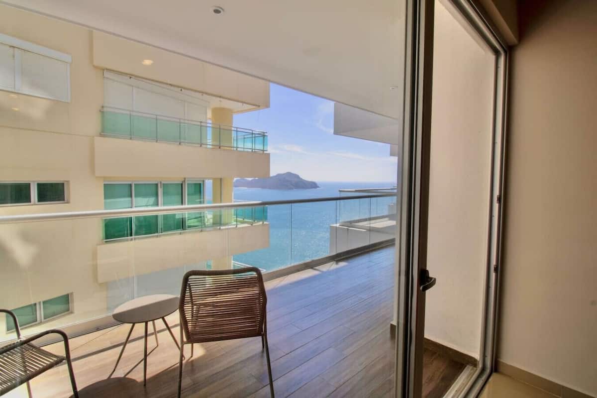 Un balcon avec vue sur la mer et les montagnes, une table et une chaise.