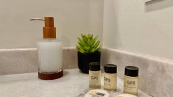 A bathroom counter with a hairdryer, a small potted plant, and four bottles labeled 'GPS'.
