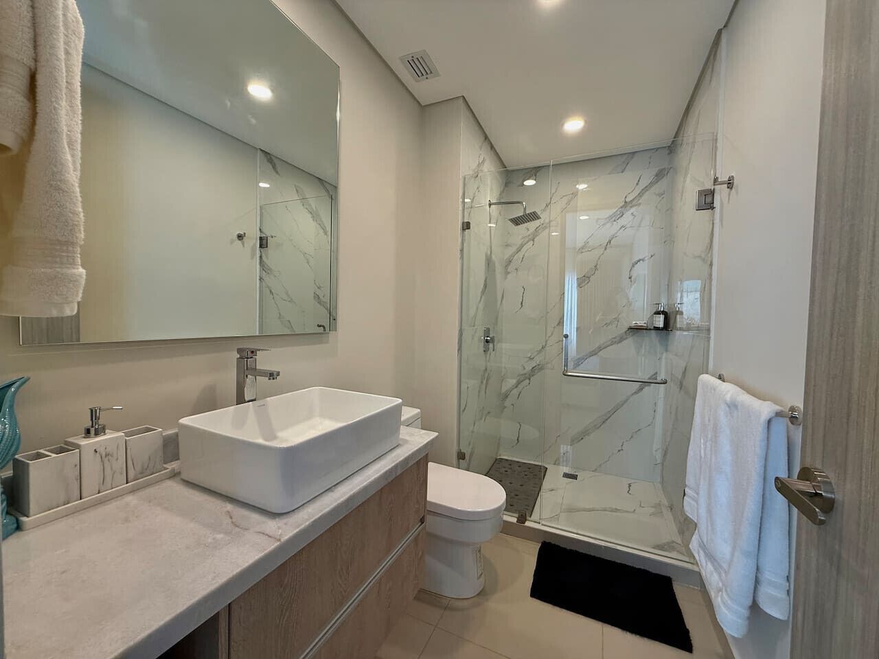 Une salle de bain moderne avec un grand lavabo blanc, des toilettes et une douche à parois de verre.