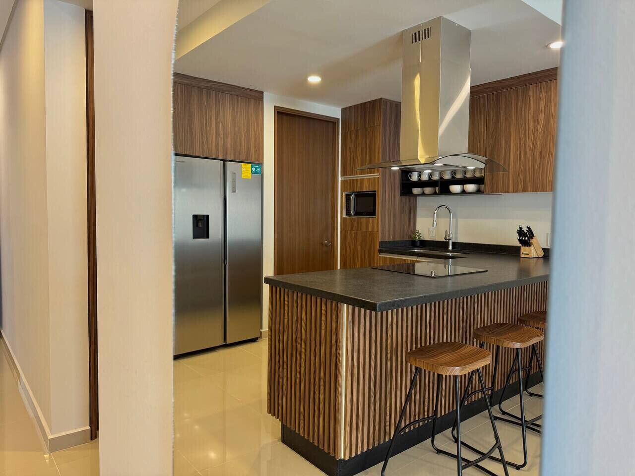 A modern kitchen with a central island, stainless steel appliances, and wooden accents.