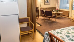 En kompakt opholdsstue med tekøkken, spiseplads med bord og stole samt en sofa.
