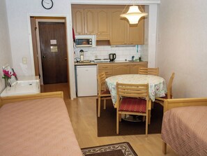 A compact room with a kitchenette, a dining table with chairs, and two beds. - Kylpylä-hotelli, huone 242 by Interhome (Ikaalinen)