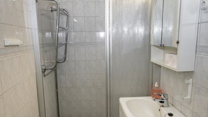 A bathroom with a shower, a sink, and a mirror. - Kylpylä-hotelli, huone 242 by Interhome (Ikaalinen)