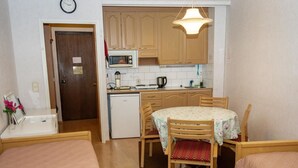 A compact room with a kitchenette, a dining table with chairs, and a bed. - Kylpylä-hotelli, huone 242 by Interhome (Ikaalinen)