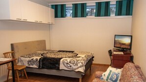 A bedroom with a bed, a desk, a chair, a television, and a sofa. - Kylpylä-hotelli, huone 152 by Interhome (Ikaalinen)