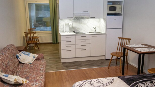 A compact room with a sofa, a dining table, a kitchen area with a microwave, and a small kitchenette. - Kylpylä-hotelli, huone 152 by Interhome (Ikaalinen)