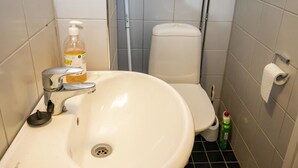 A bathroom with a white sink, toilet, and a bottle of hand soap. - Kylpylä-hotelli, huone 152 by Interhome (Ikaalinen)