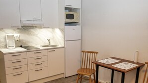 A compact kitchen with a sink, microwave, and a small dining area with two chairs and a table. - Kylpylä-hotelli, huone 152 by Interhome (Ikaalinen)