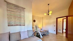 Une pièce comprenant un canapé, un lit, une tapisserie murale, un lustre et une porte en bois.