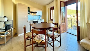 Une cuisine compacte avec un coin repas, un four encastré et une vue sur l’extérieur par l’ouverture de la porte.