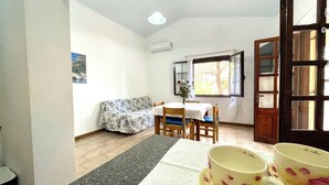Un coin repas avec une table dressée pour deux personnes, un canapé et une fenêtre avec des rideaux.