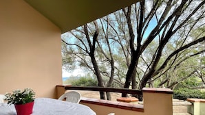 Un balcon avec une table, des chaises et un pot de fleurs.