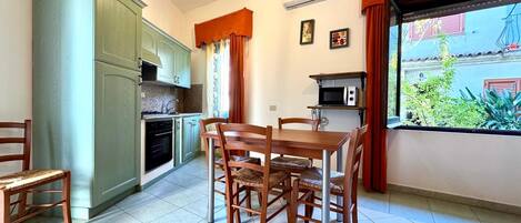 A compact kitchen with a dining area, a microwave, and a window with curtains.