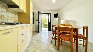 Uma cozinha compacta com fogão, armários e um espaço de refeições com cadeiras e mesa.