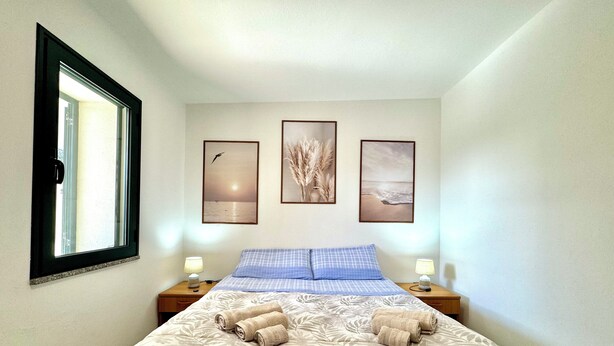 Um quarto com uma cama, duas mesinhas de cabeceira e três quadros na parede.