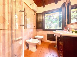 Un baño con ducha, inodoro, bidé y lavamanos.