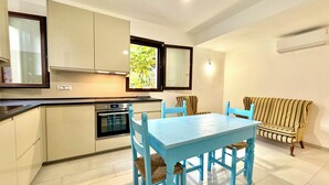 Una cocina compacta con electrodomésticos modernos, un área de comedor con sillas azules y un sofá a rayas.