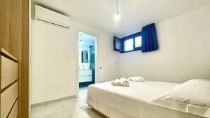 Hotellihuone, jossa on sänky, avoimesta ovesta näkyvä kylpyhuone ja ikkuna, jossa on verhot.