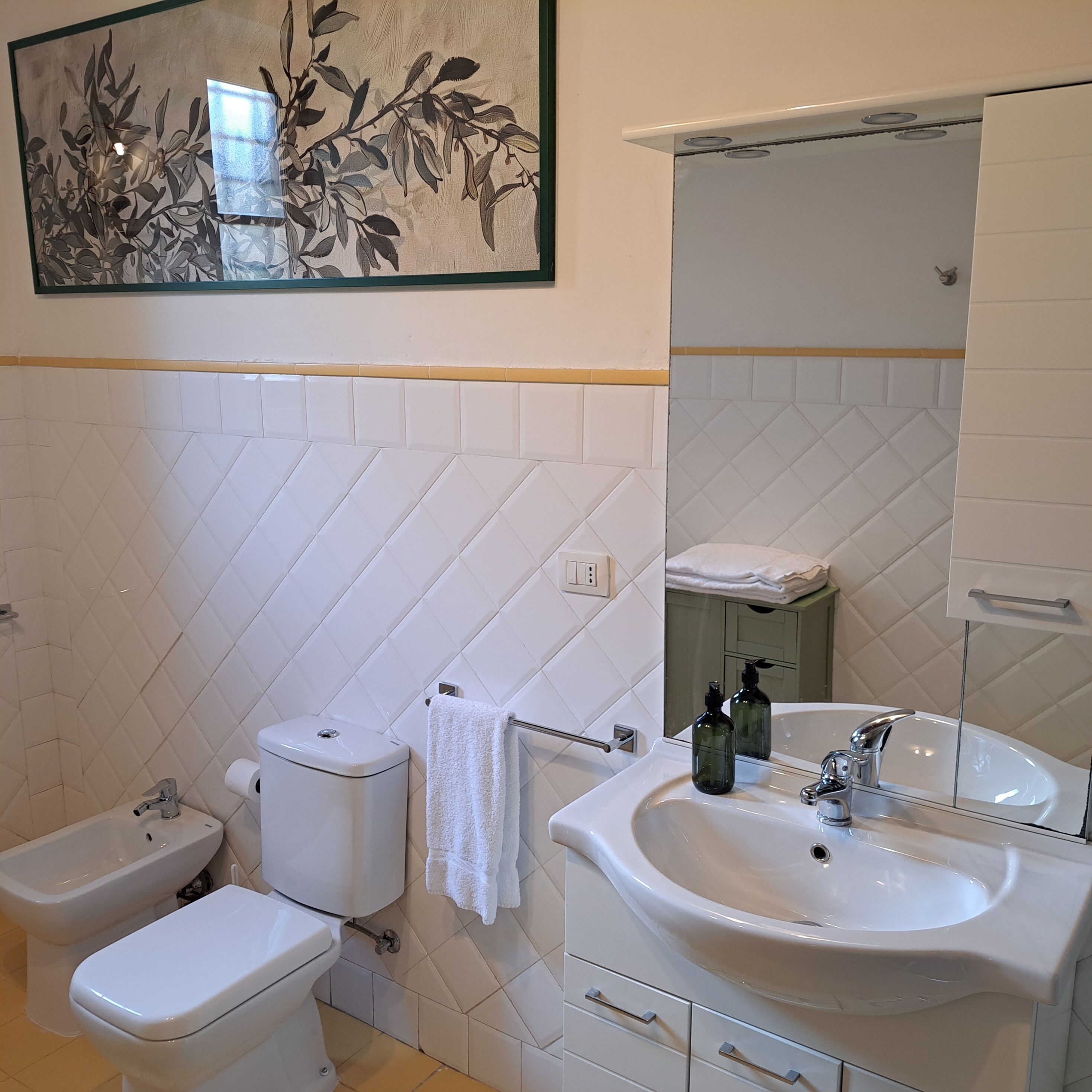 Un baño con inodoro, bidé, lavabo y espejo.