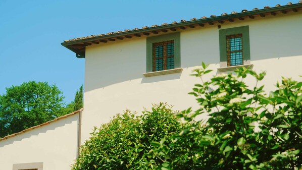 A building with a white facade, green window frames, and a tiled roof.