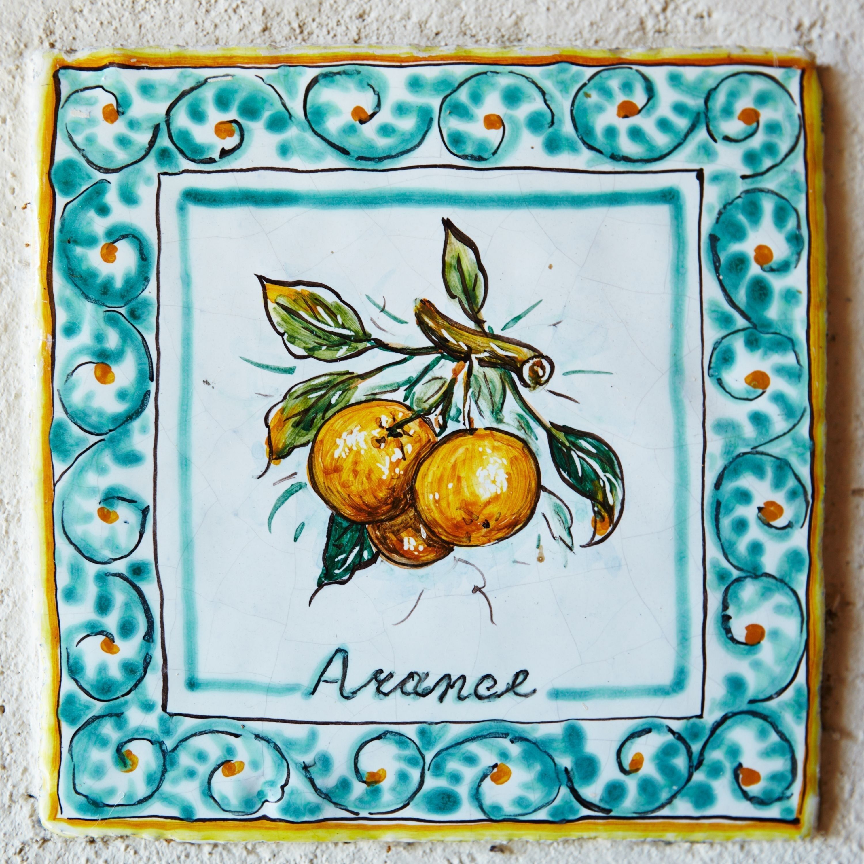 A tile with a citrus fruit design and the word "Avance" on it.