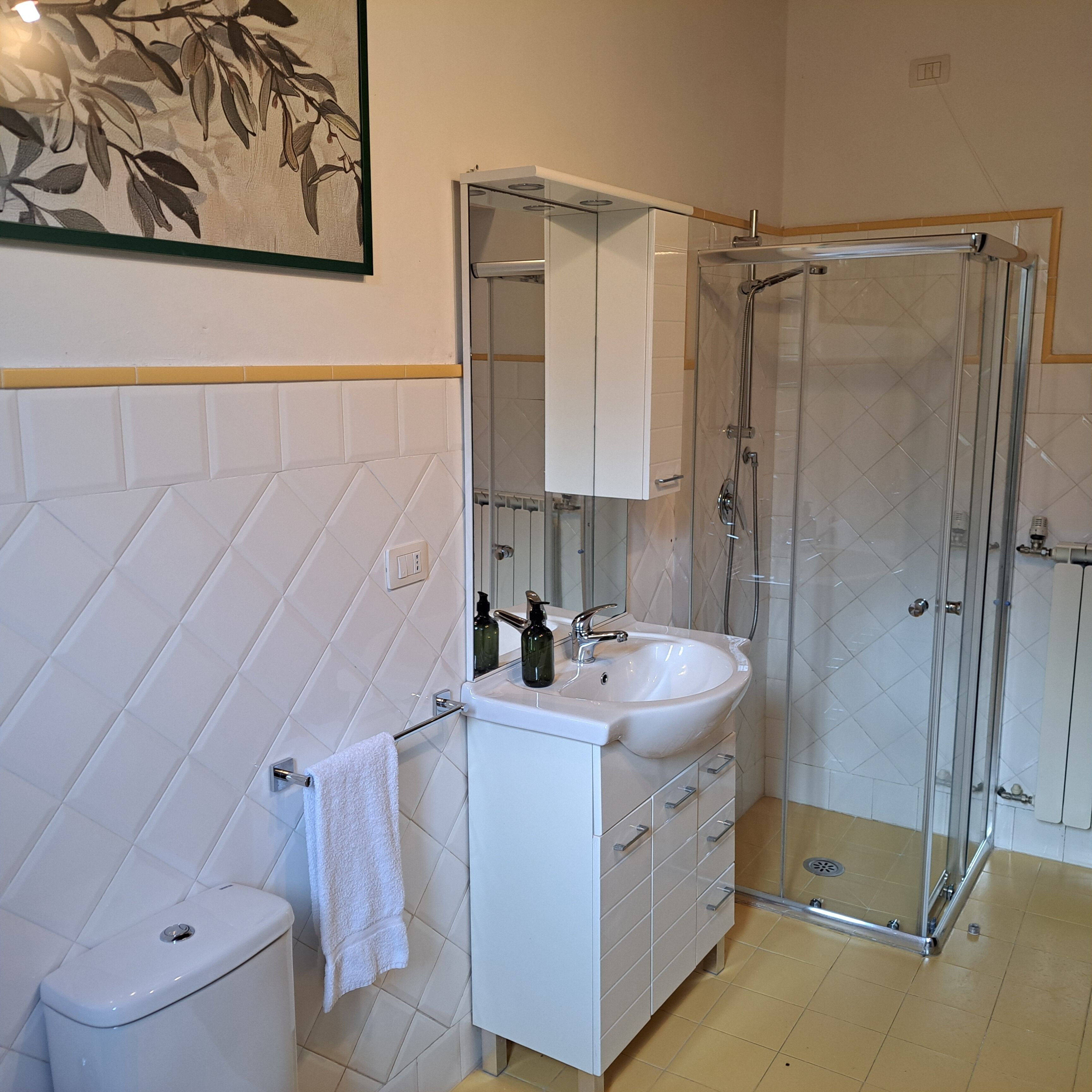 Baño con inodoro, lavabo y cabina de ducha de vidrio.