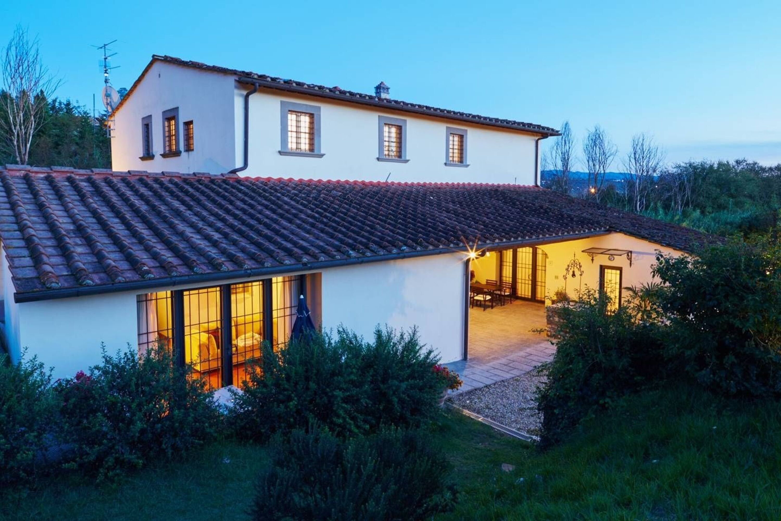 A two-story house with a tiled roof, large windows, and a patio area.