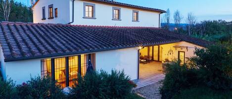 A two-story house with a tiled roof, large windows, and a patio area.