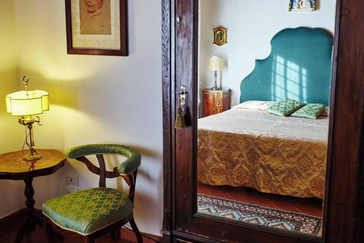 A room with a bed, a chair, a lamp, and a small table.