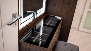 Un banc en bois avec un plateau en verre, une porte dotée d’une poignée et un miroir placé au-dessus.
