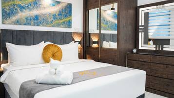 A modern hotel room with a large bed, a wooden headboard, a mirror, and a decorative wall piece.
