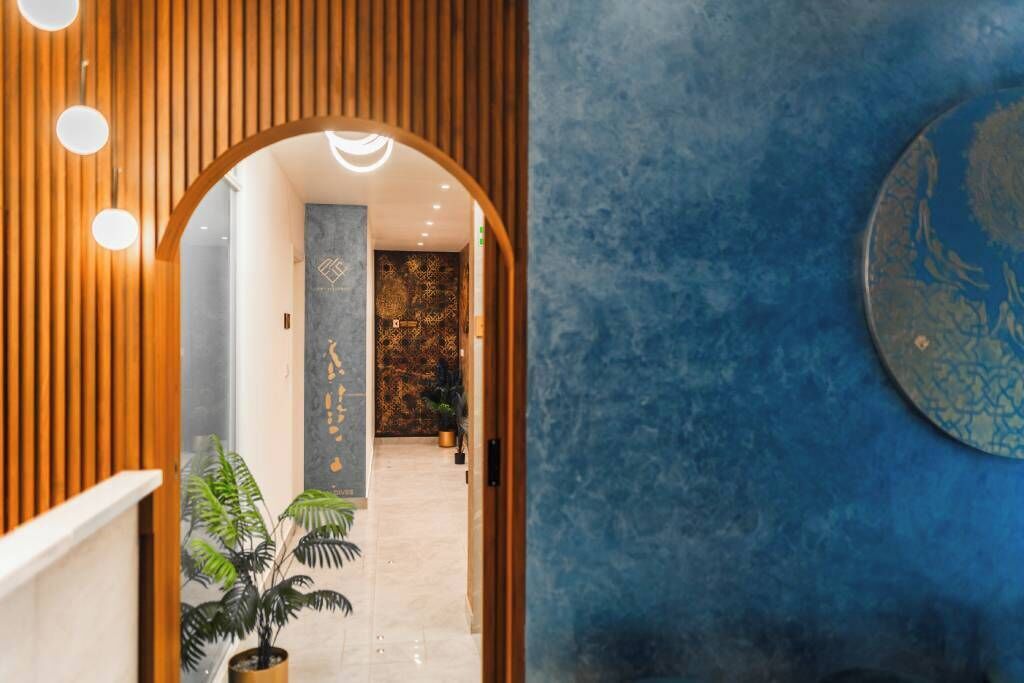 Un pasillo con un panel de pared de listones de madera, una planta en maceta y una pared azul con textura y un diseño circular.