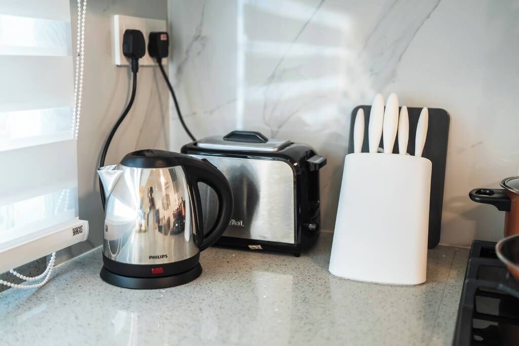 Et køkken med en Philips kaffemaskine, en brødrister og et knivblok på bordpladen.