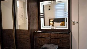 A room with a large mirror, wooden dresser, and a bench.