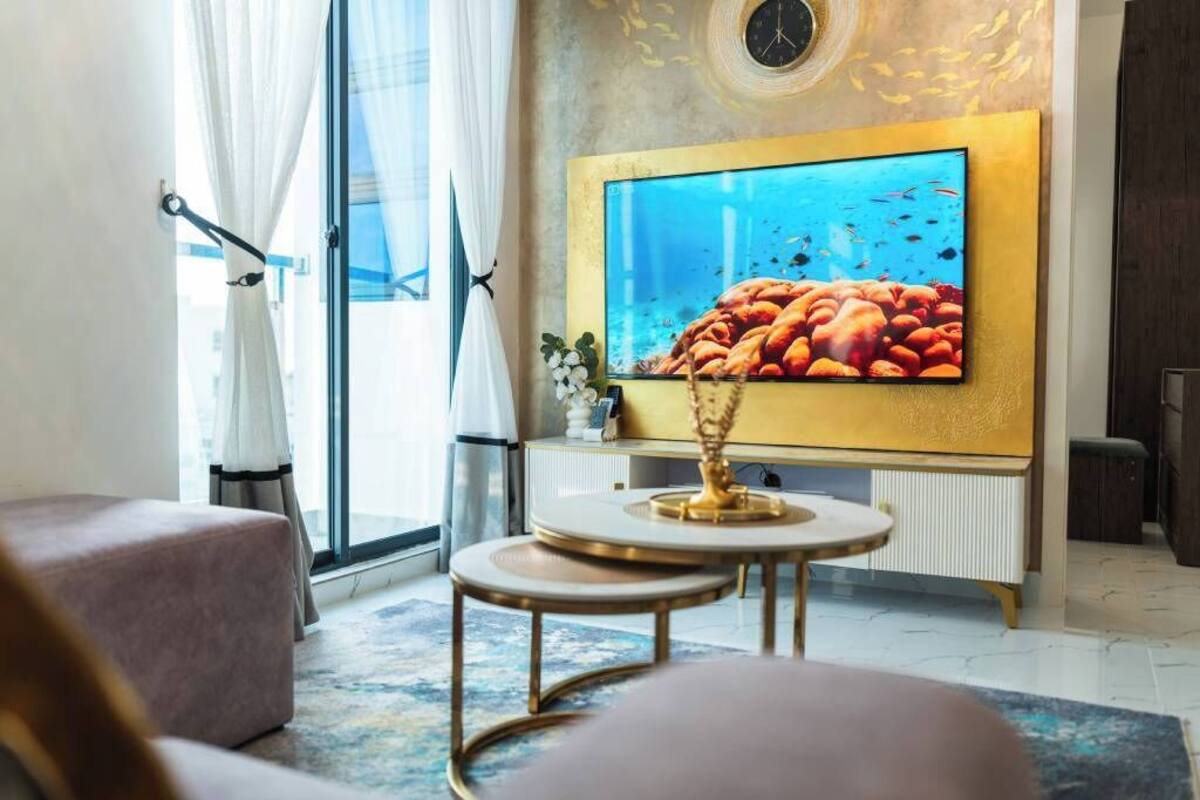 Una sala de estar moderna con un televisor de pantalla plana grande, una mesa de centro redonda y un área de estar cómoda.