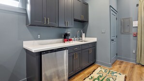 A kitchen with dark cabinets, a stainless steel dishwasher, and a white countertop.