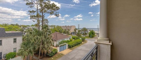 A residential street with houses, a large pine tree, and a clear sky.