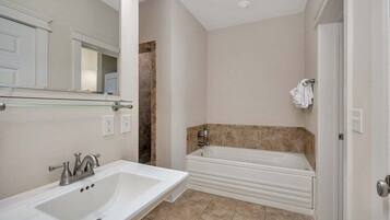 A bathroom with a white sink, a bathtub, and a mirror.