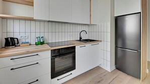 Une cuisine moderne avec des armoires blanches, un réfrigérateur en acier inoxydable, un four encastré et un plan de travail en bois.