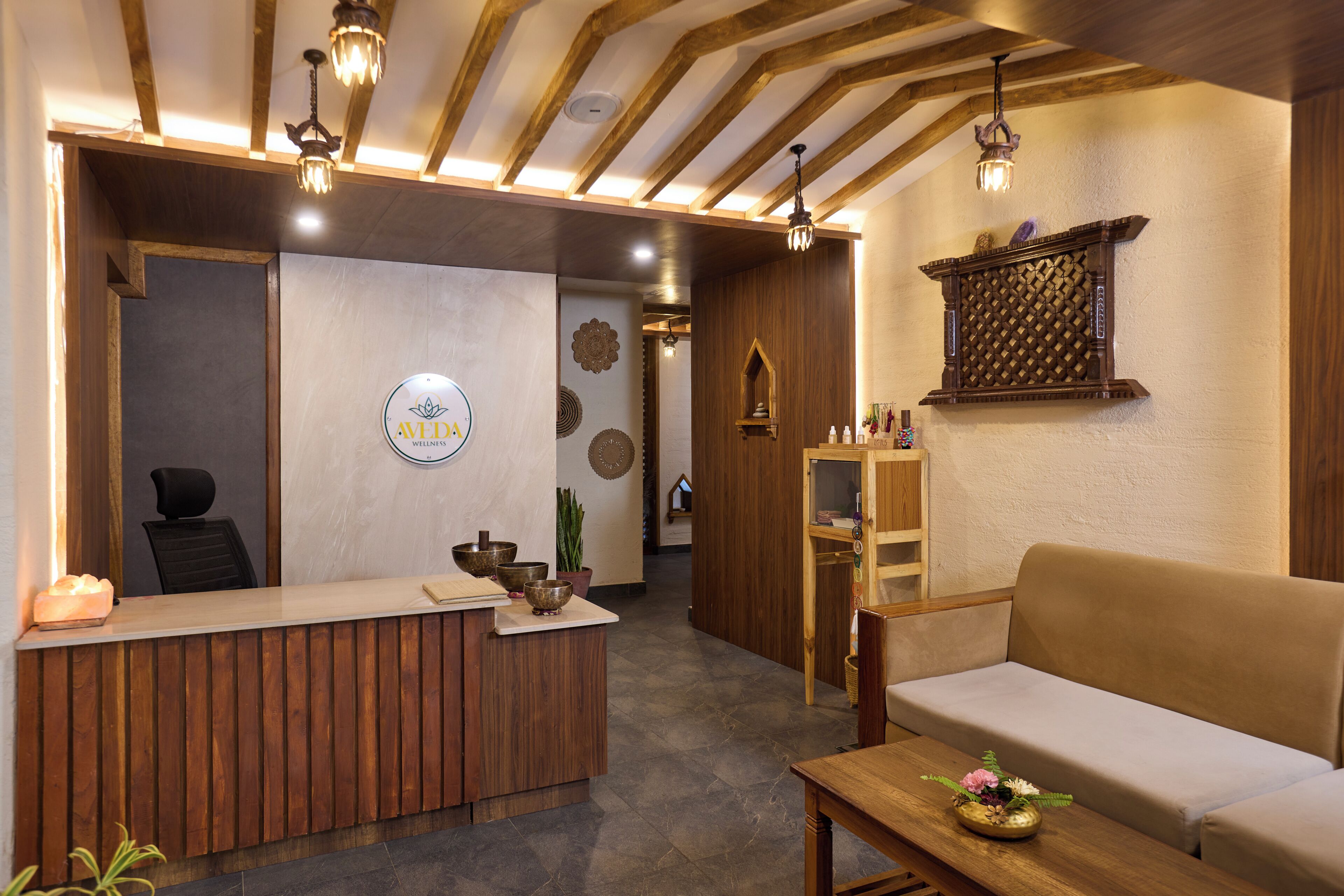 Un área de recepción con un mostrador de madera, un sofá y una estantería de pared con objetos decorativos.