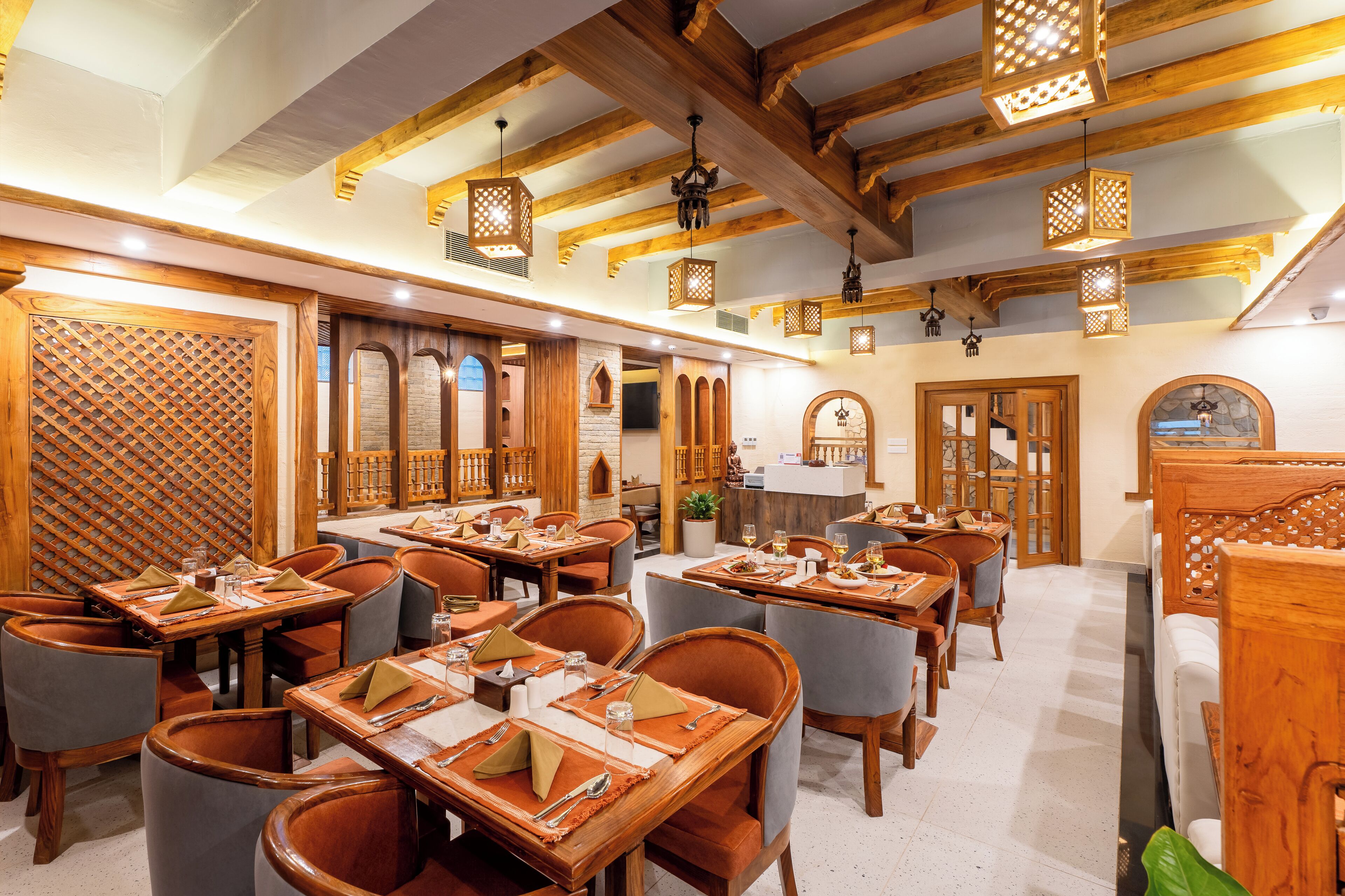 Un restaurante con mesas y sillas de madera, una barra y faroles colgantes.