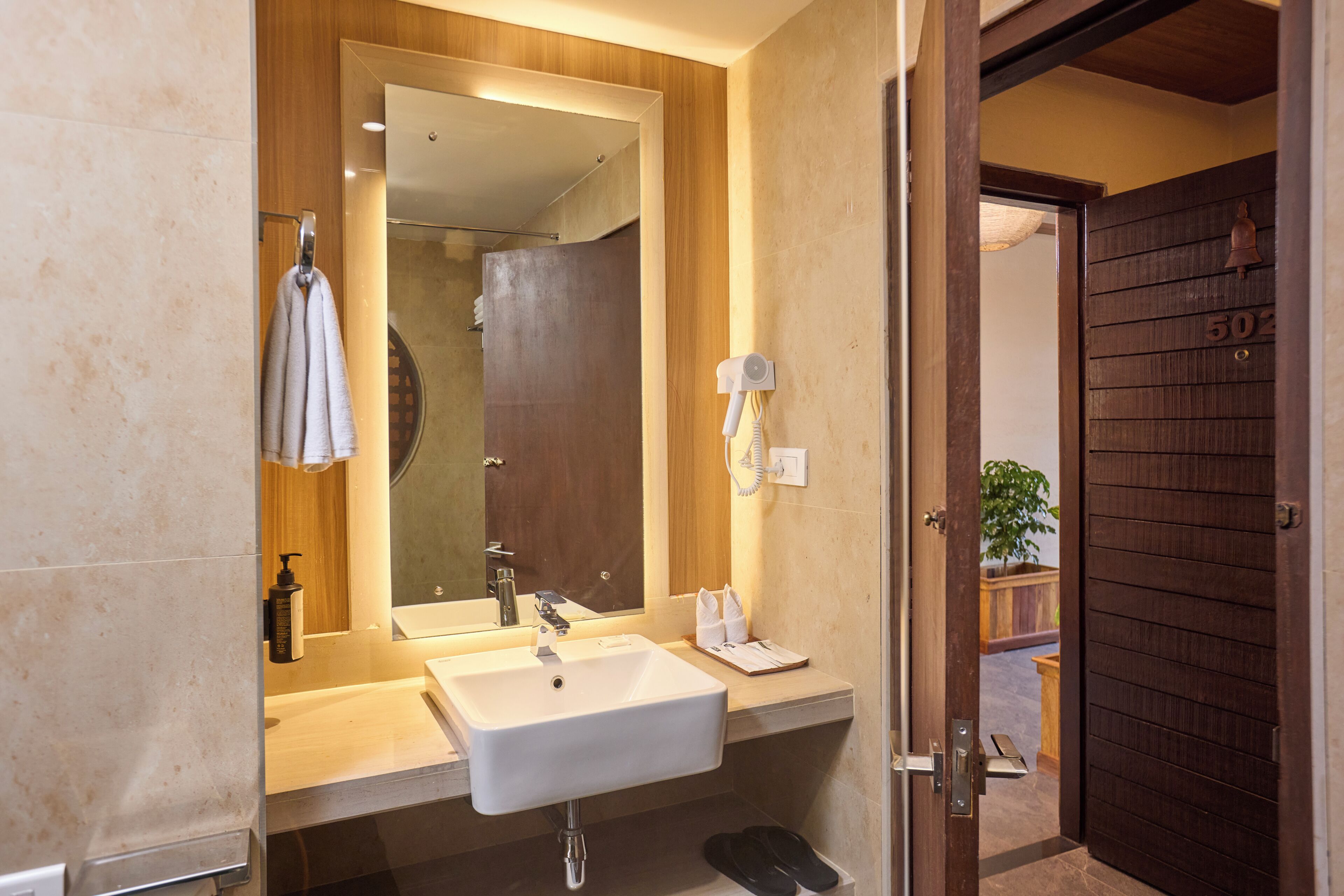 A bathroom with a sink, mirror, towel rack, and a door leading to a shower area.