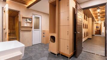 A modern bathroom with a wooden cabinet, a white bathtub, and a sauna.