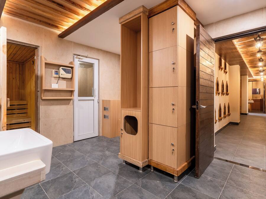 A modern bathroom with a wooden cabinet, a white bathtub, and a sauna.