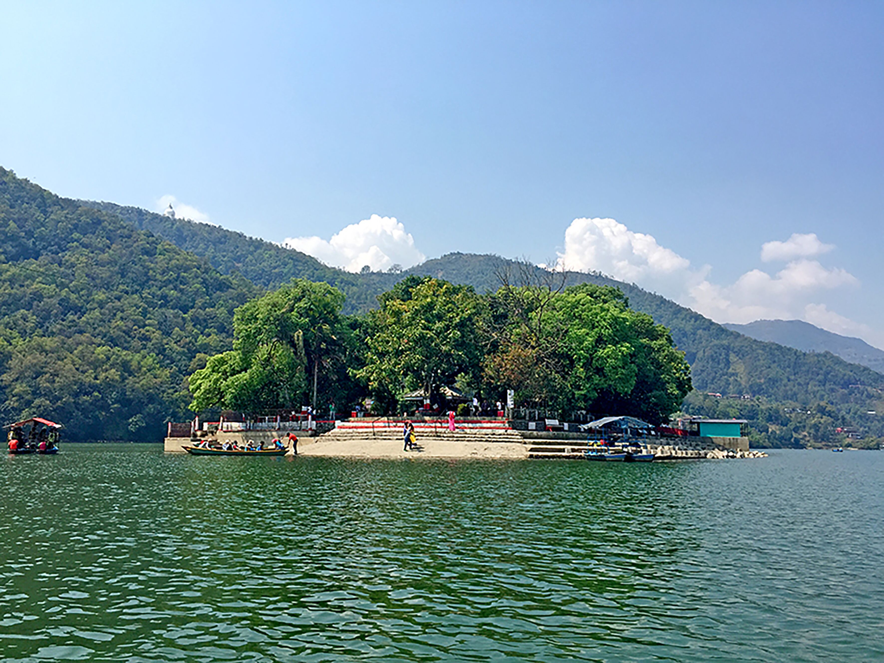 Un resort a orillas del lago con un muelle, embarcaciones y montañas al fondo.